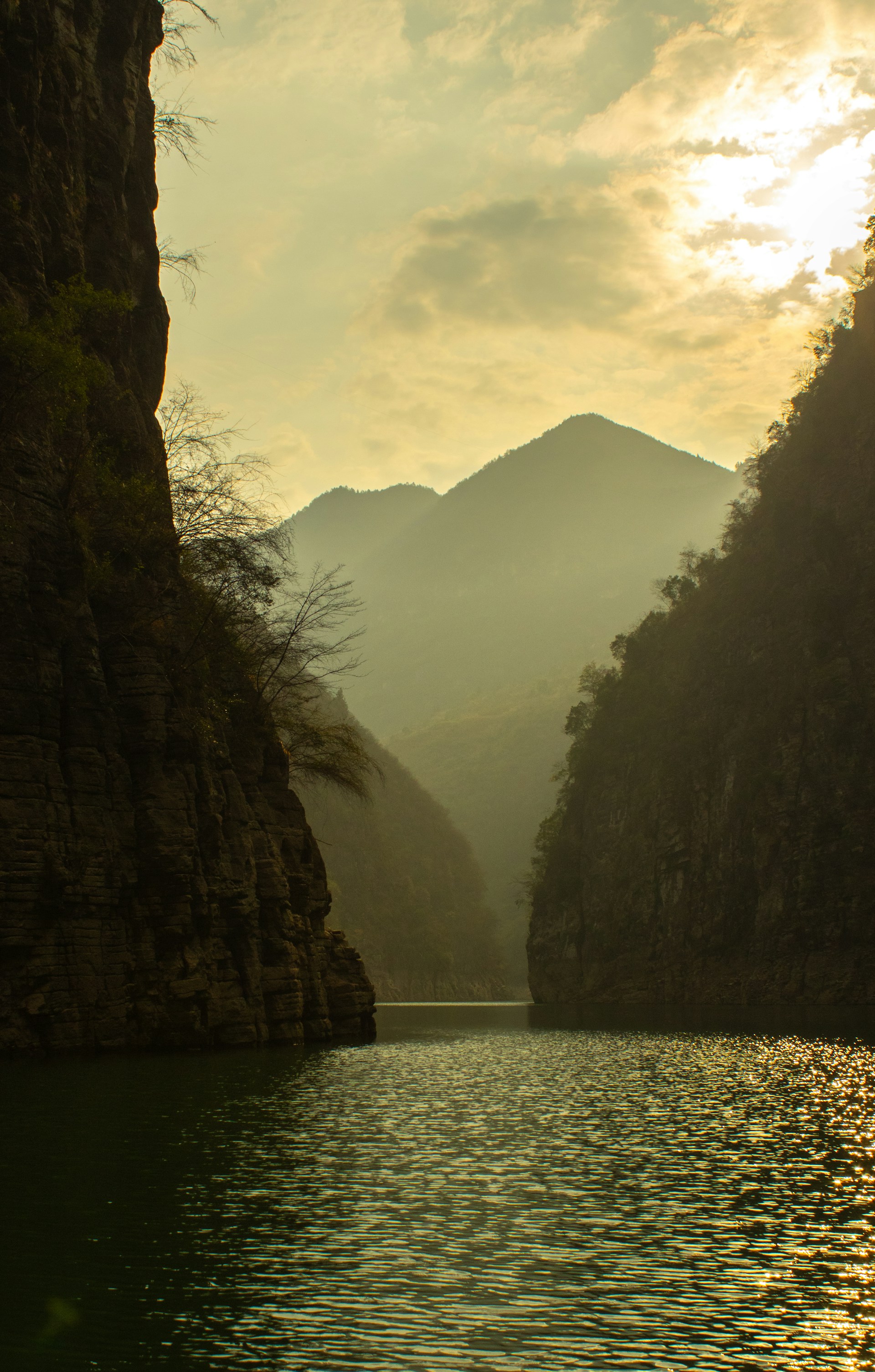 a body of water surrounded by mountains under a cloudy sky