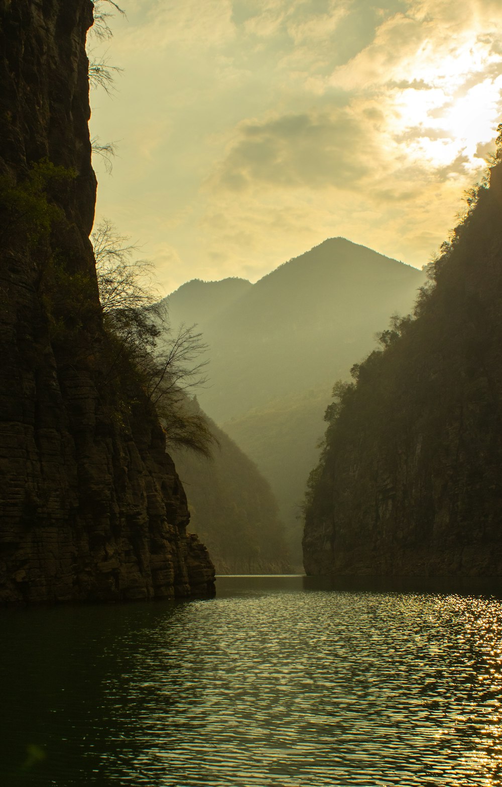 a body of water surrounded by mountains under a cloudy sky