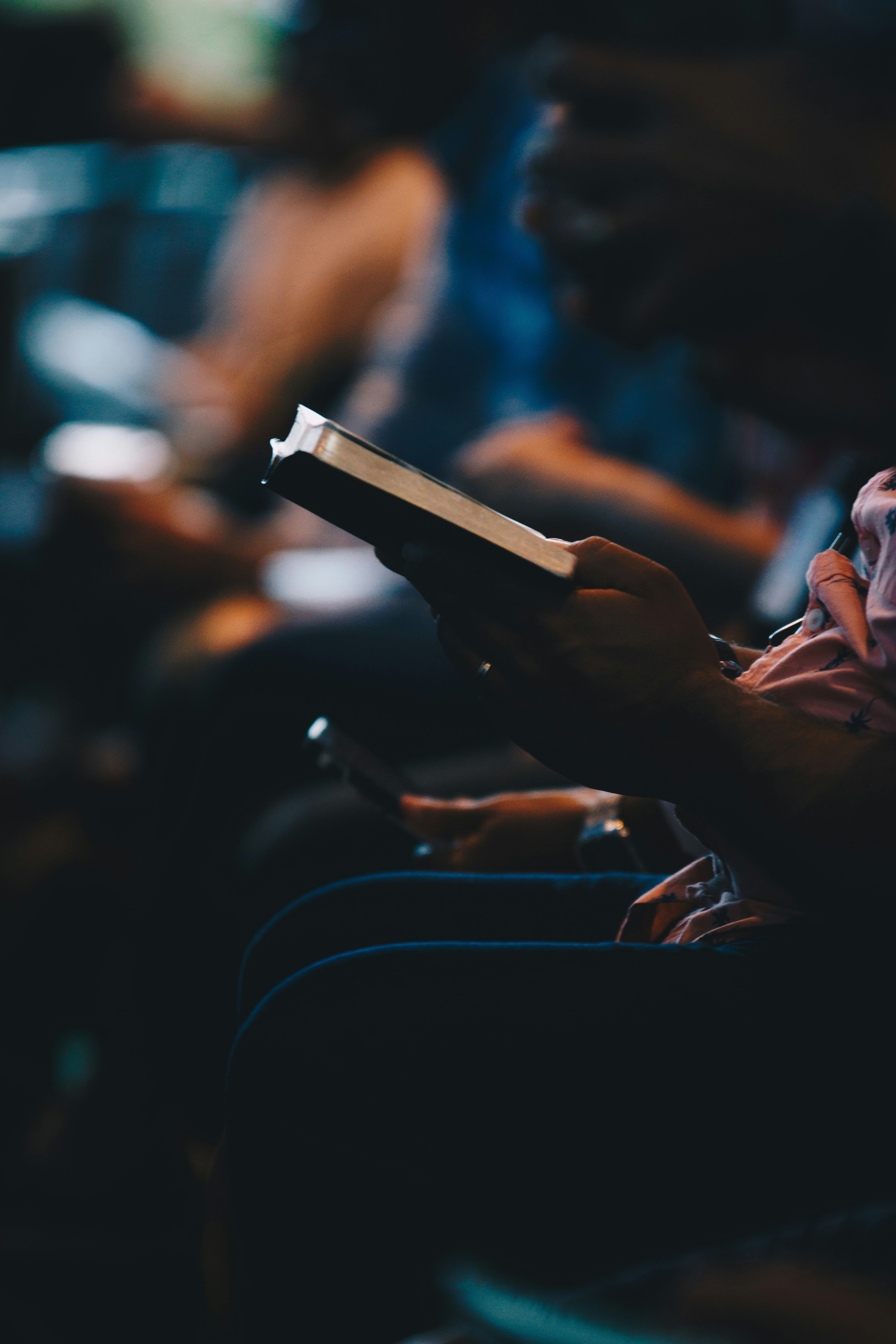 Person reading a book in dim warm light, intimate cozy atmosphere, deep shadows