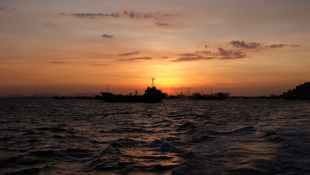 a sunset over a body of water with a boat in the distance