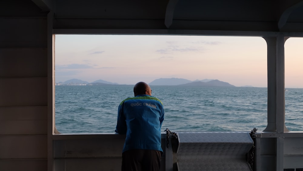 ein Mann, der auf einem Boot steht und auf den Ozean blickt