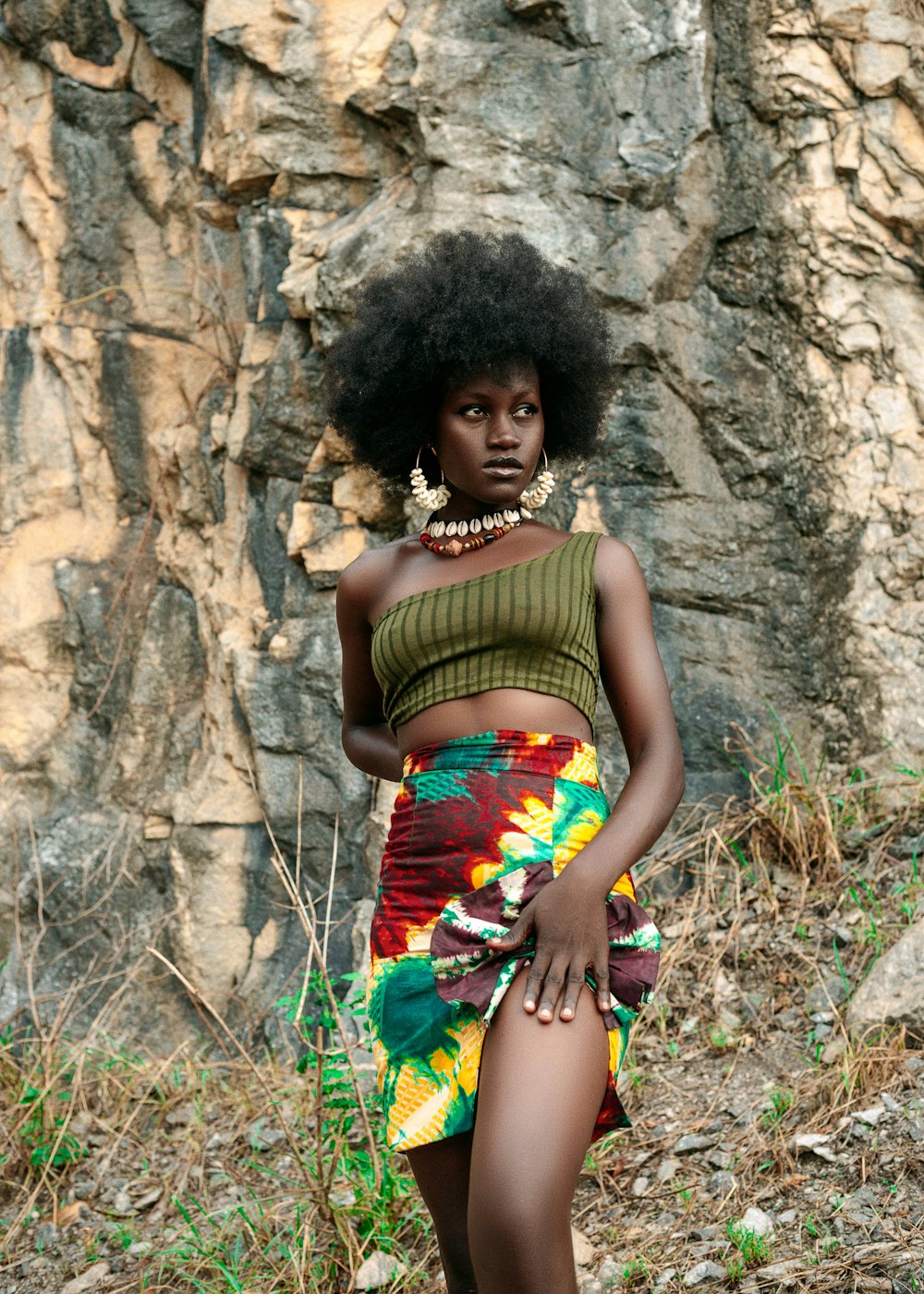 a woman with an afro standing in front of a rock