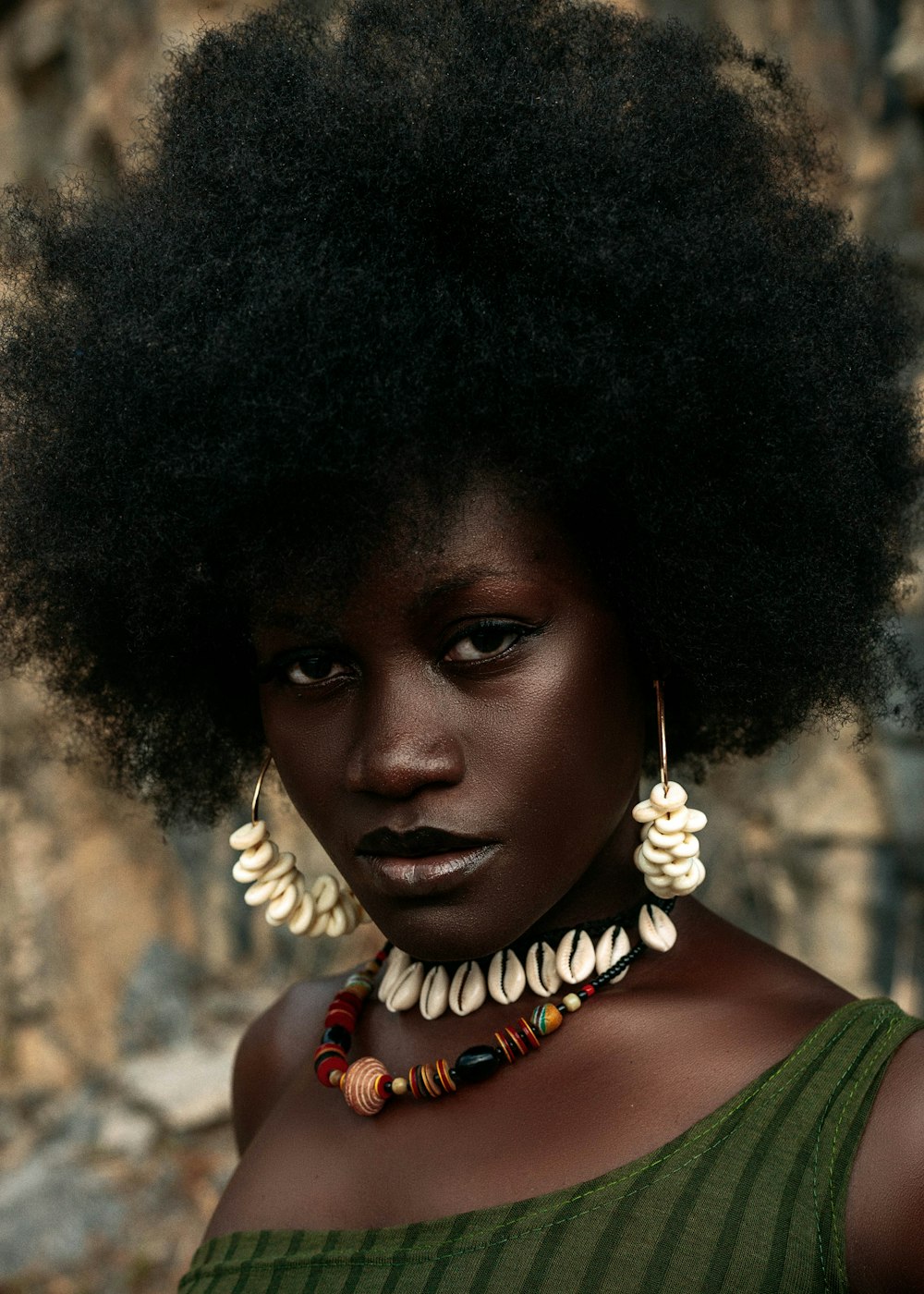 a woman with an afro wearing a necklace and earrings