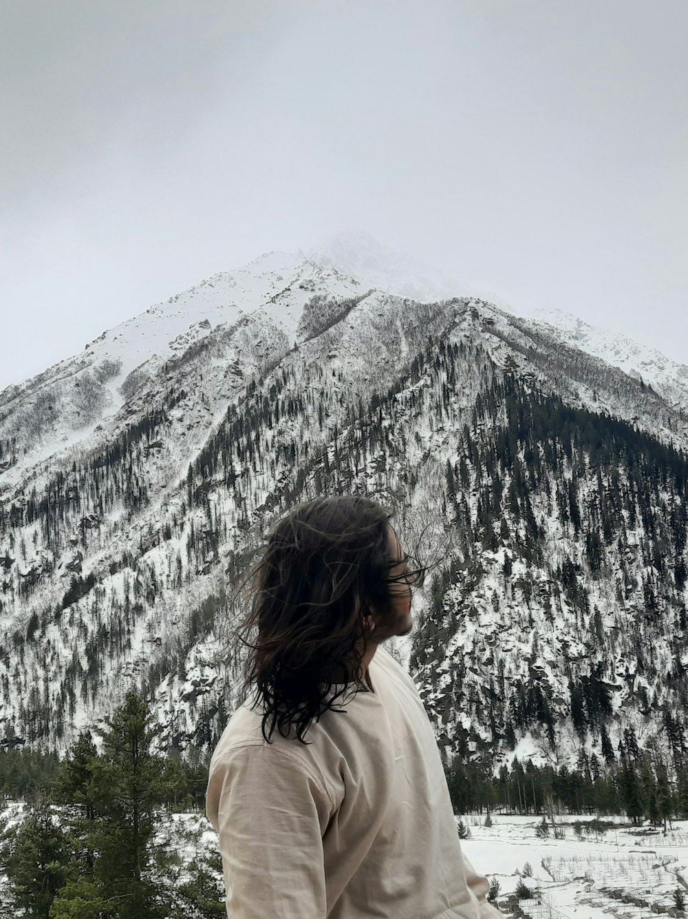 a man standing in front of a snow covered mountain