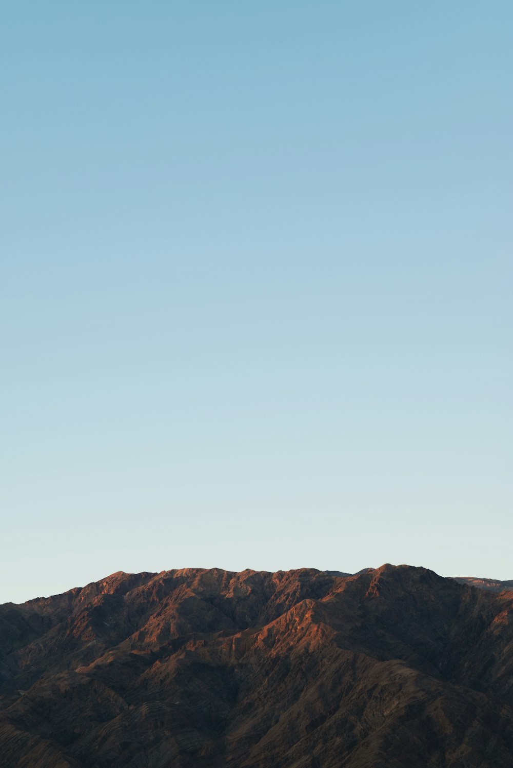 a plane flying high in the sky over a mountain range