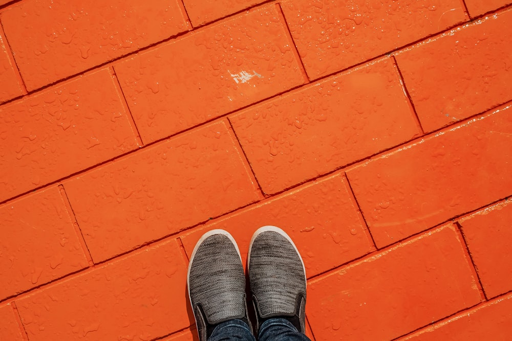 a person standing in front of an orange brick wall