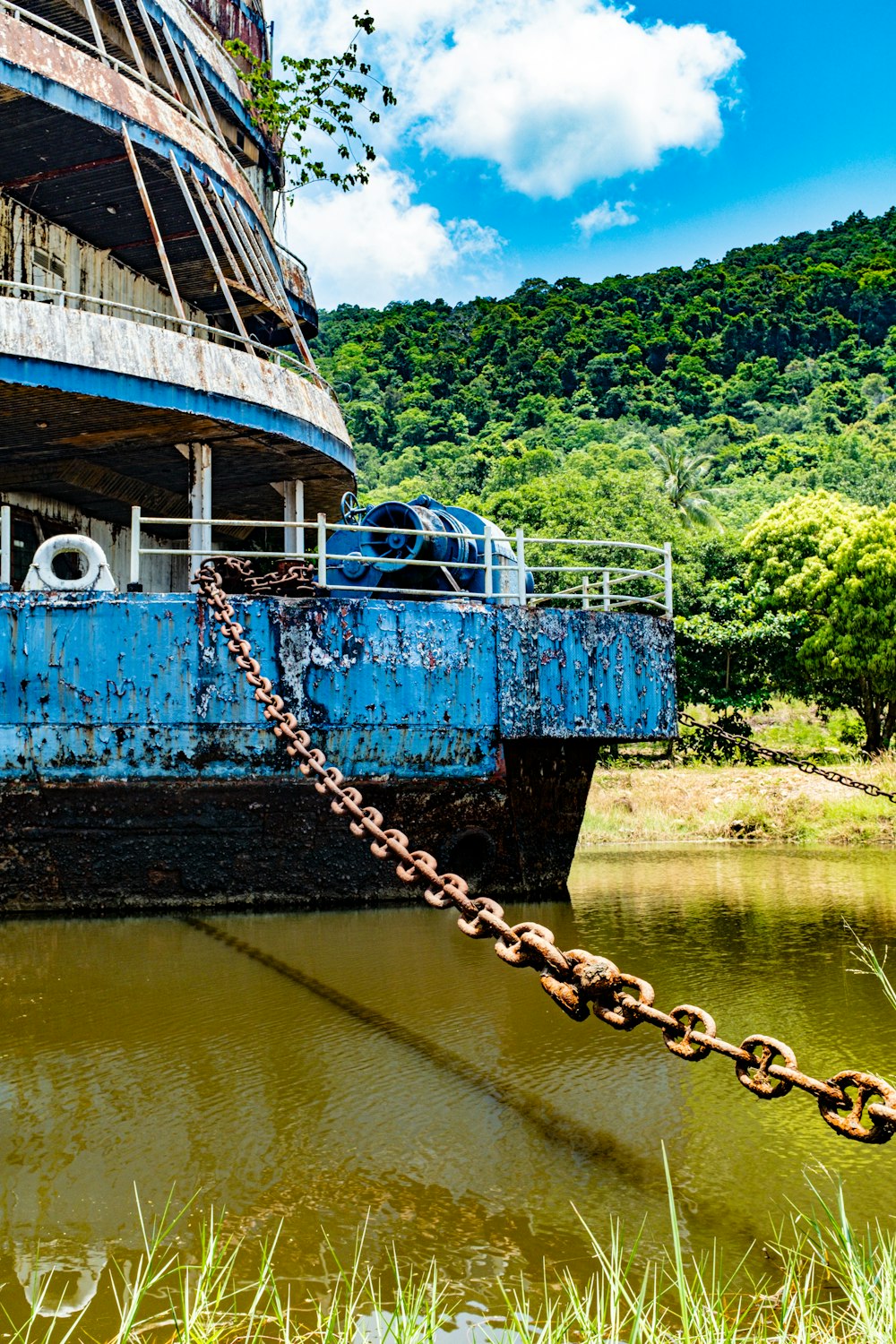 a rusted blue boat sitting on top of a body of water