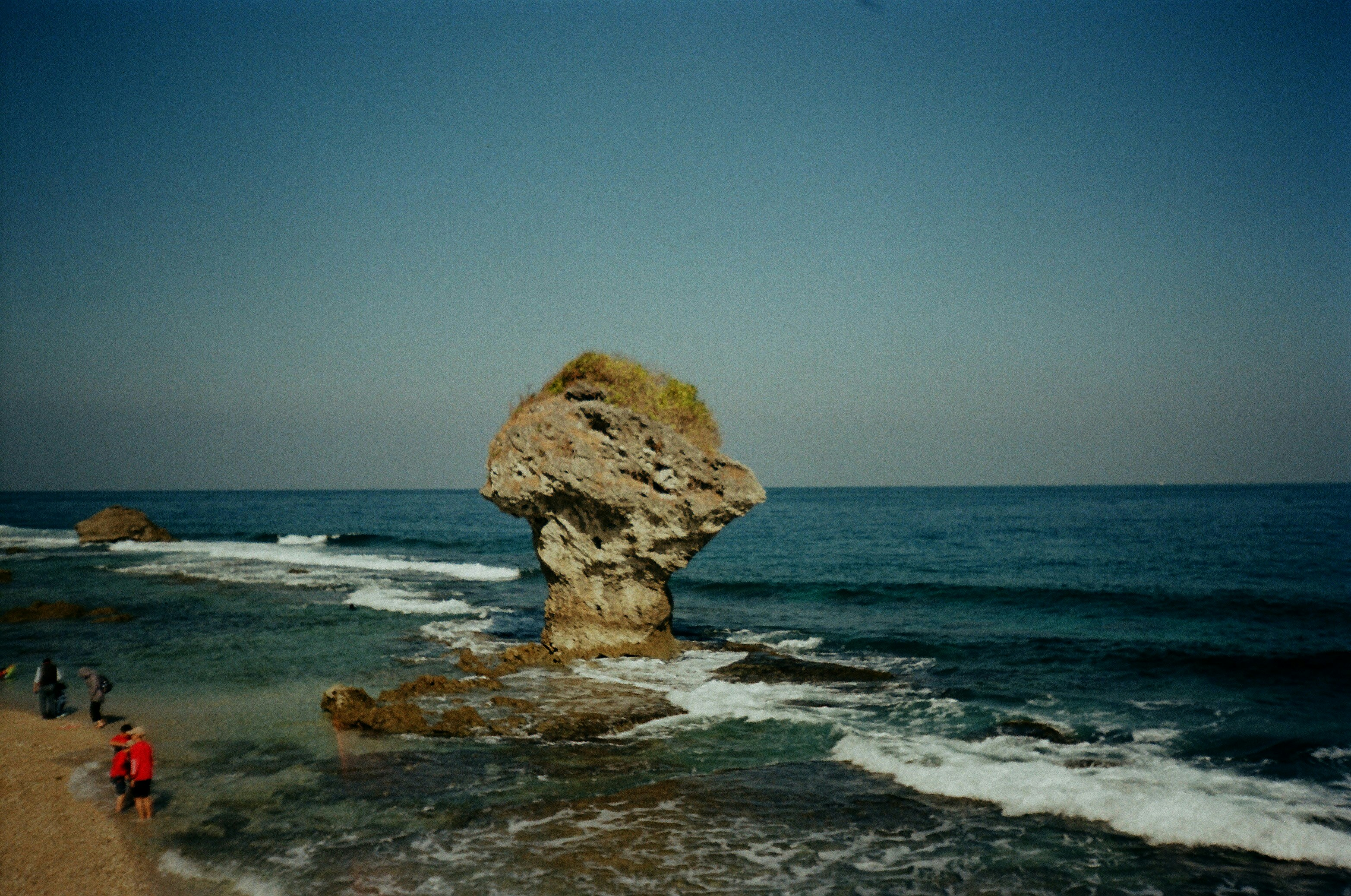 a group of people standing on top of a beach next to the ocean
