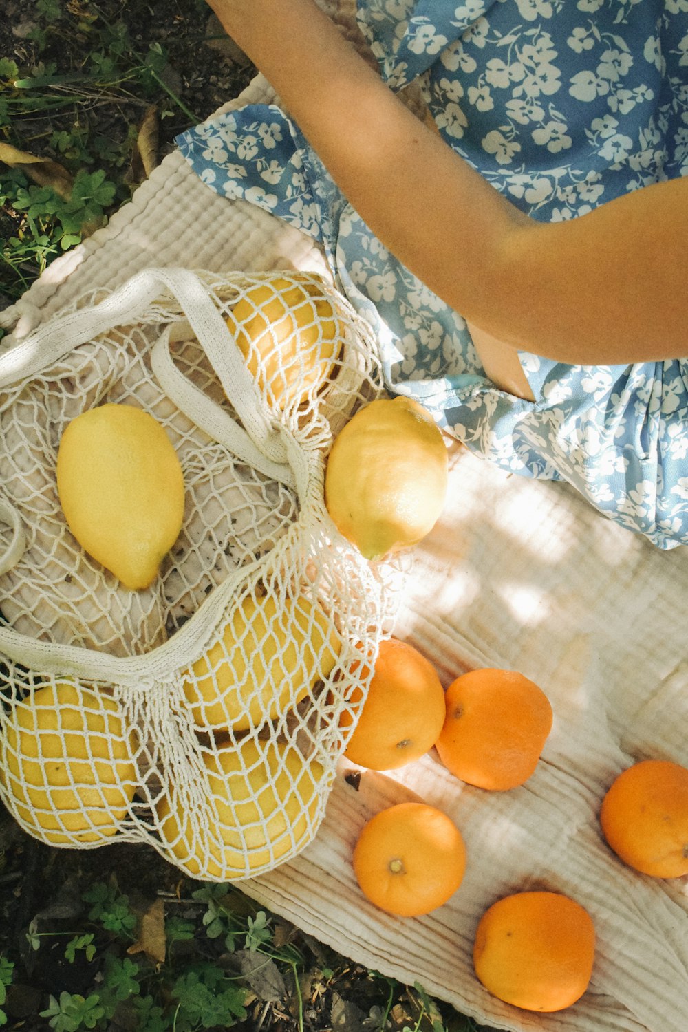 a woman holding a bag full of oranges and apples