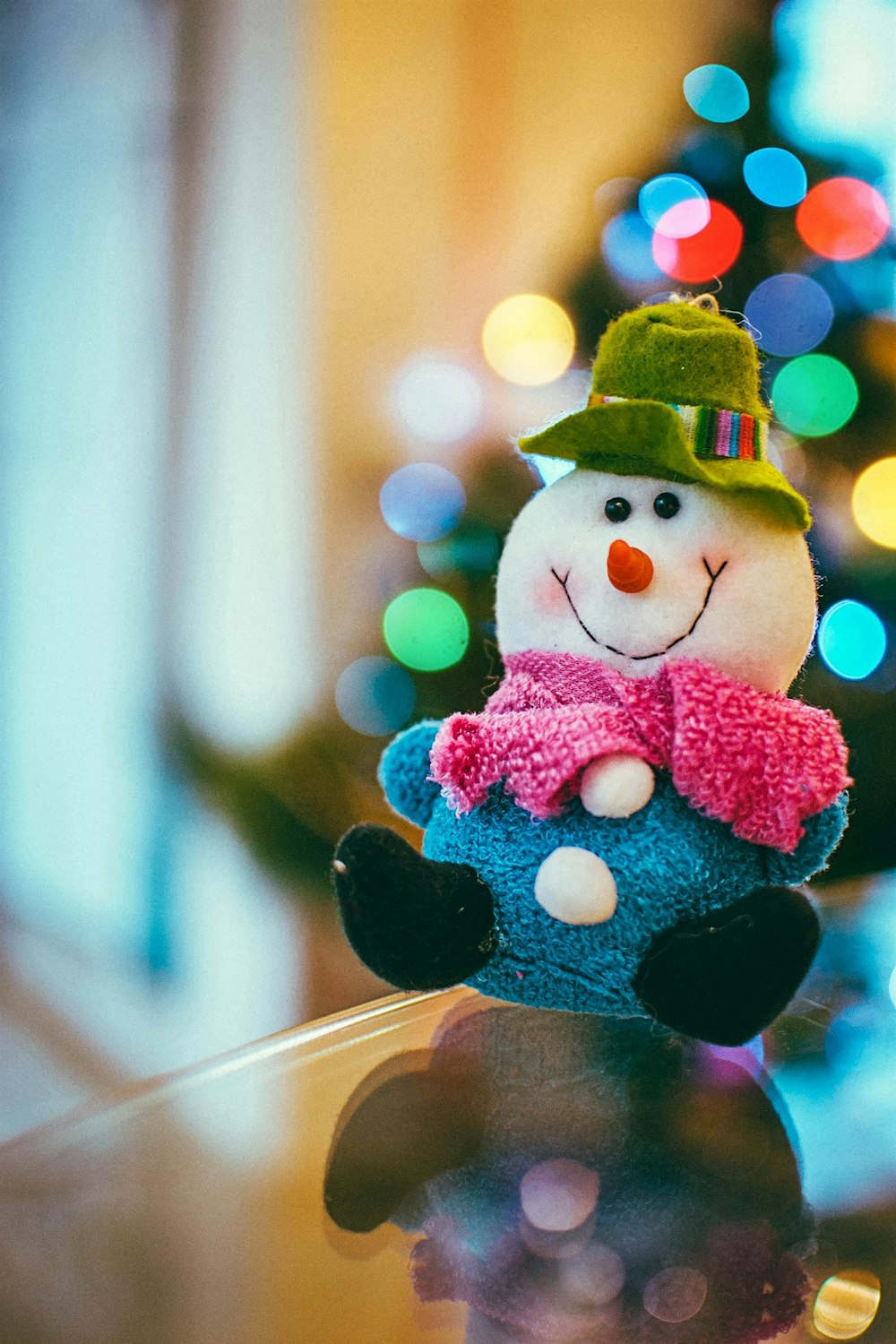 a snowman sitting on top of a table next to a christmas tree