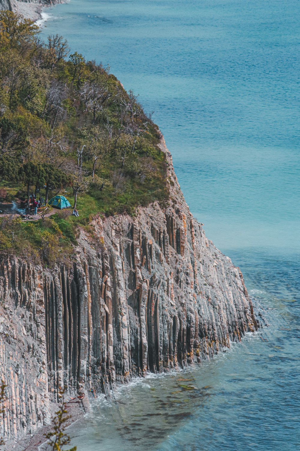 a boat is on the water near a rocky cliff