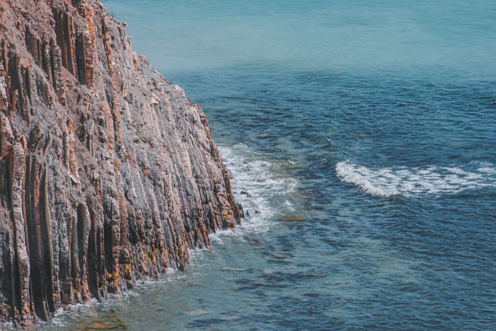 a boat is in the water near a rocky cliff