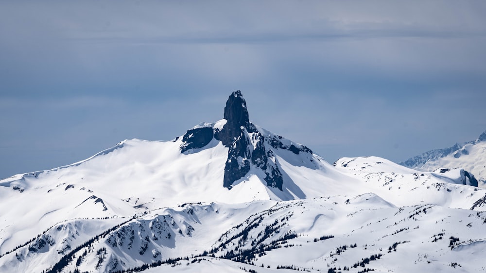 a mountain covered in snow under a cloudy sky