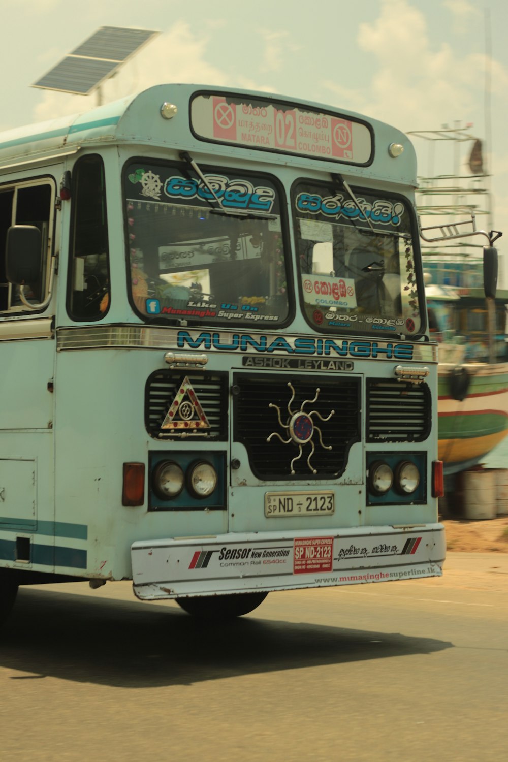 a blue bus driving down a street next to a building