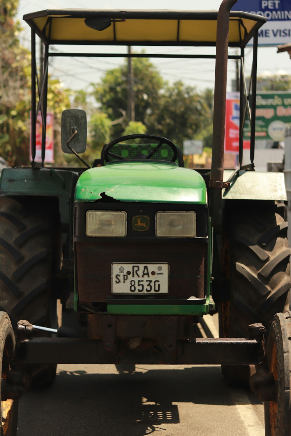 a green tractor is driving down the street