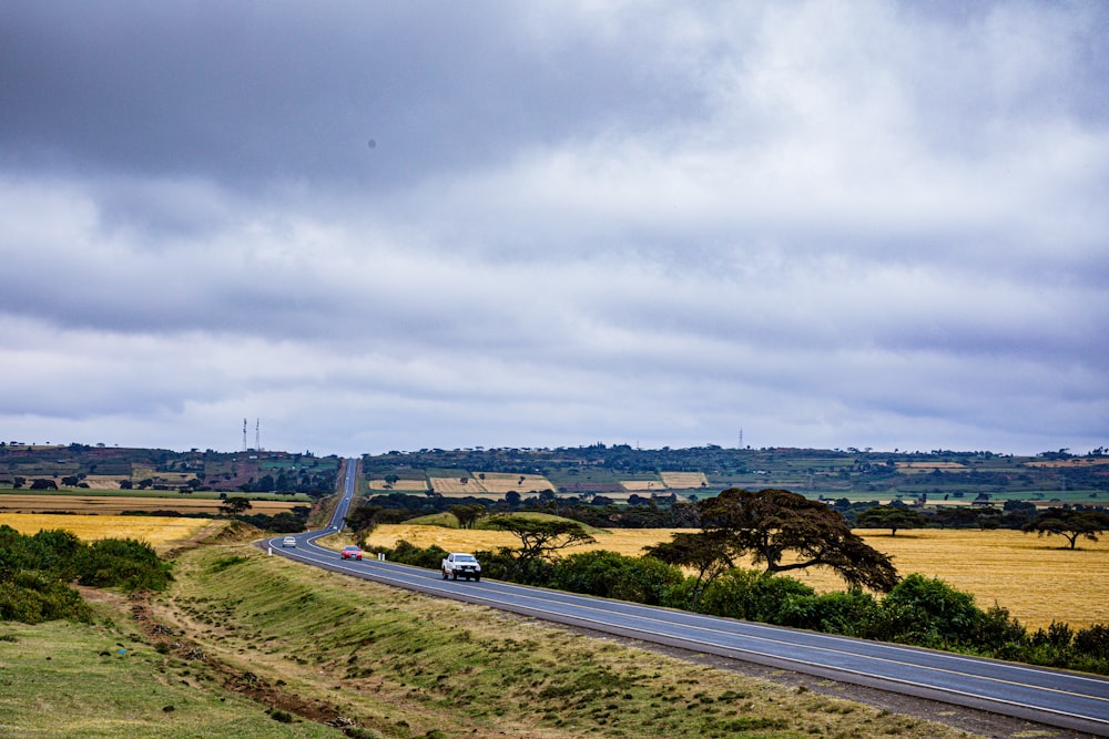 a car driving down a road in the middle of a field