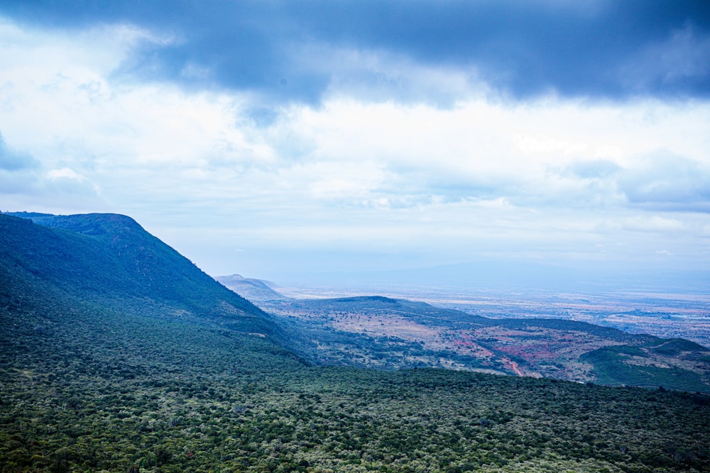 a scenic view of a valley and mountains under a cloudy sky