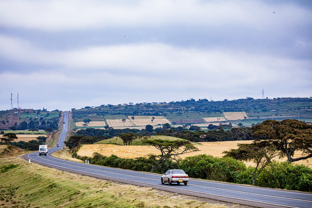 a car driving down a road with a hill in the background