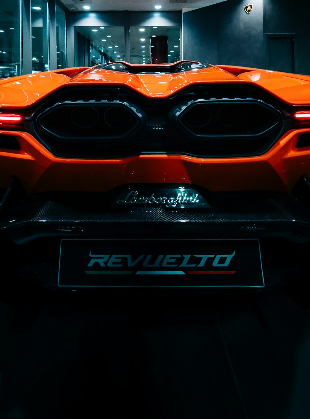 the front of an orange sports car in a dark room