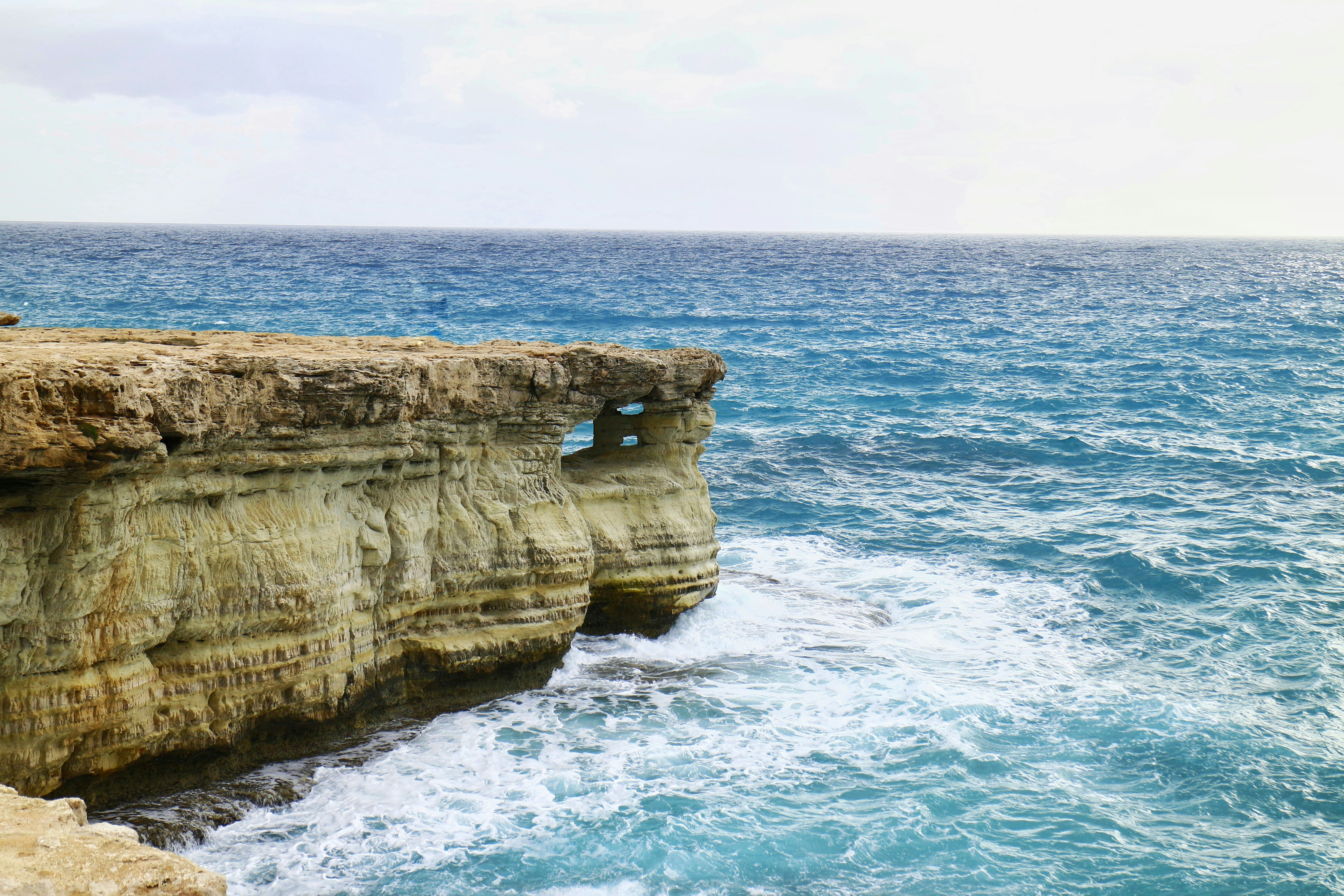 a rocky cliff with a hole in the middle of it, 