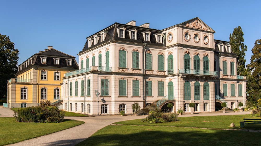 a large white building with green shutters on a sunny day