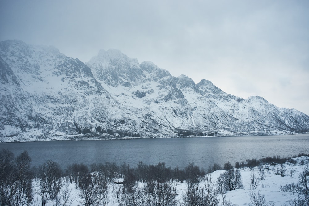 a snow covered mountain with a lake in the foreground