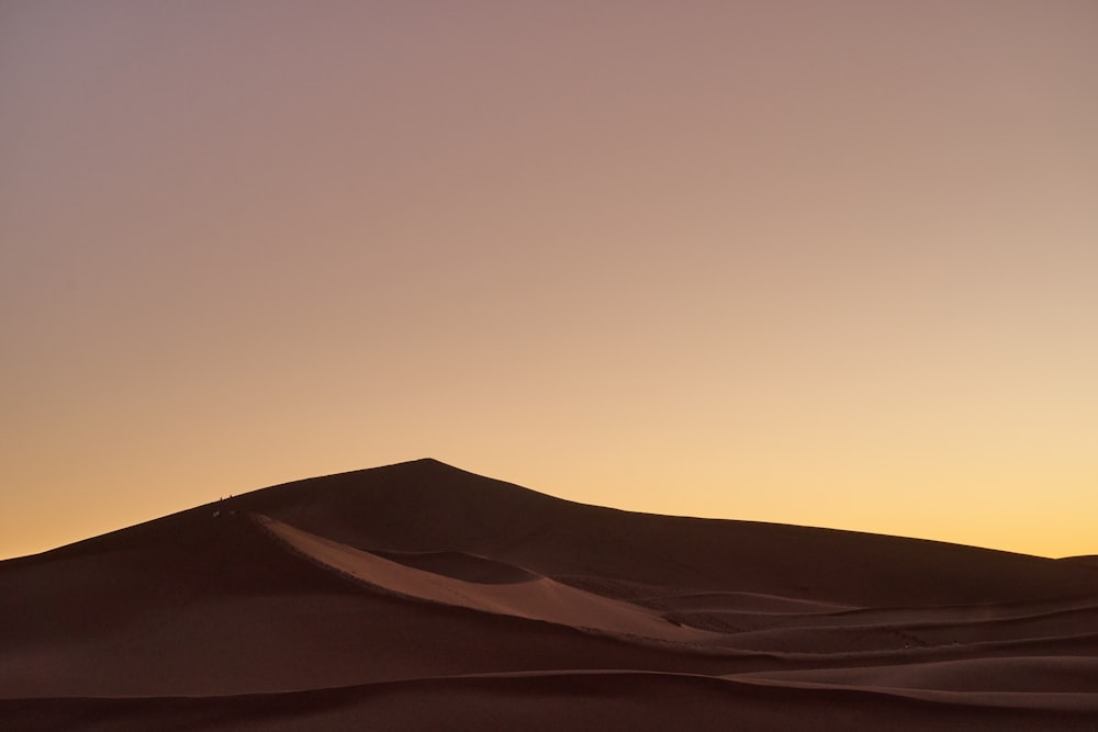 the sun is setting in the distance over the sand dunes