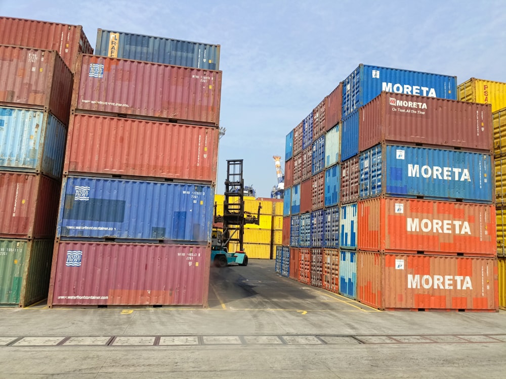a forklift is moving a large stack of shipping containers