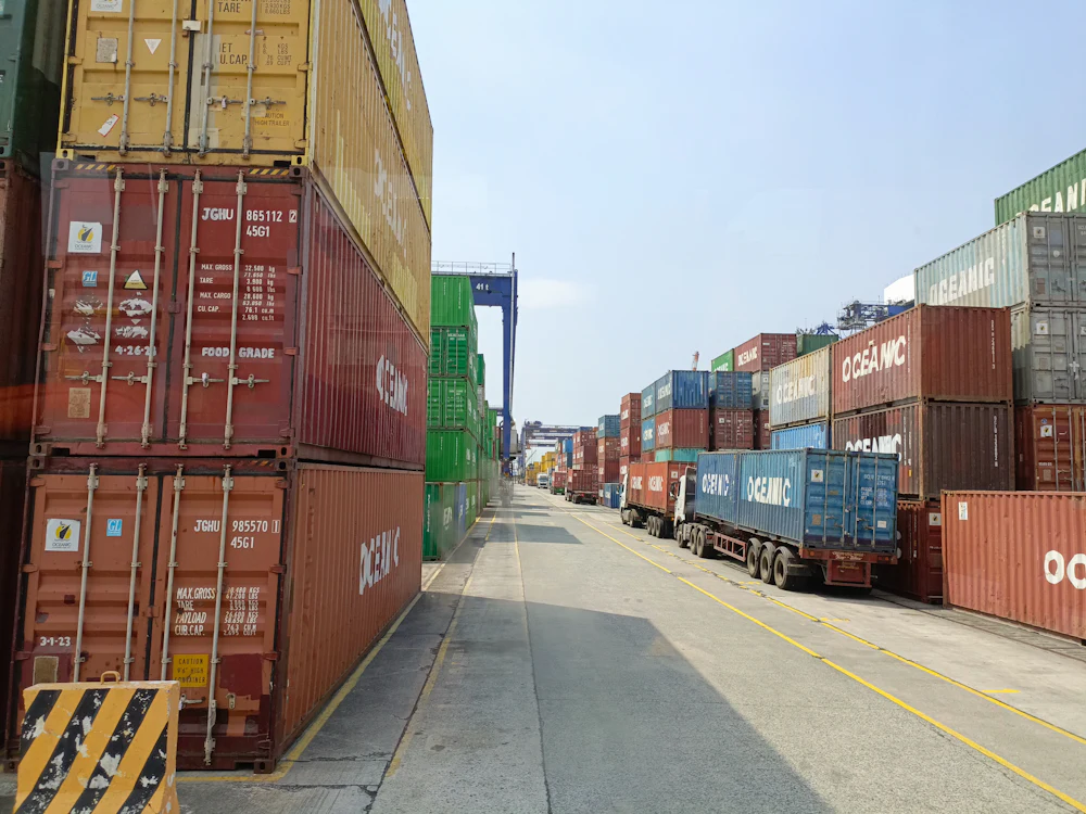 Shipping containers and haulage trucks staged at a container terminal before loading