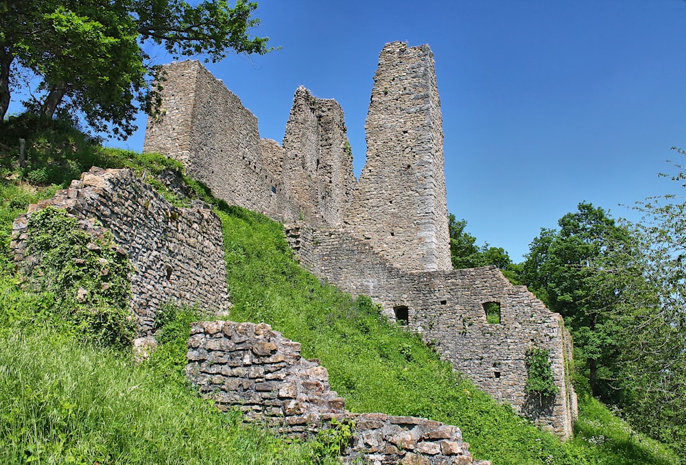 a stone castle sitting on top of a lush green hillside