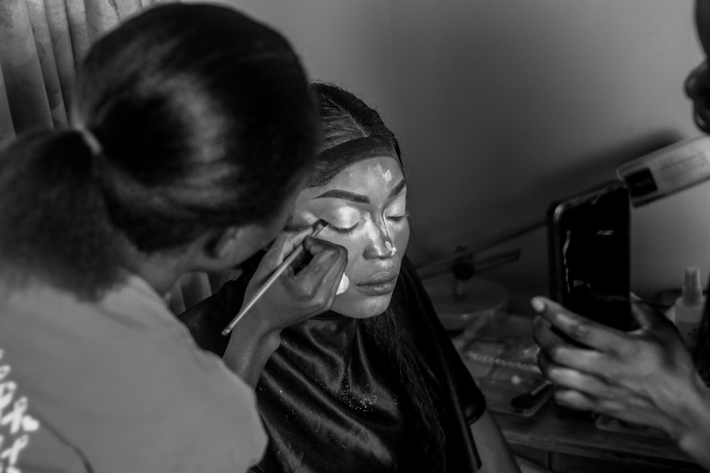 a black and white photo of a woman using a cell phone