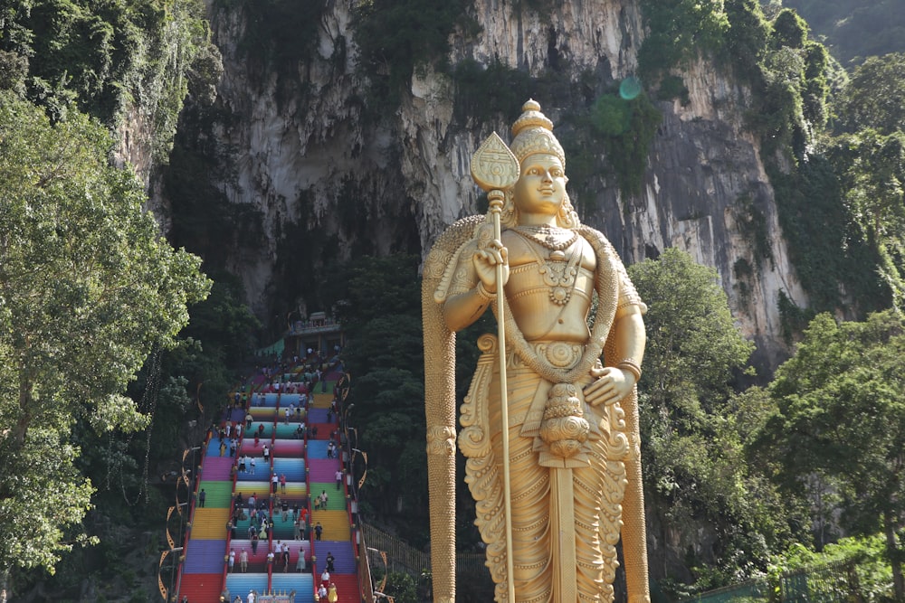 a large statue of a man holding a staff in front of a mountain