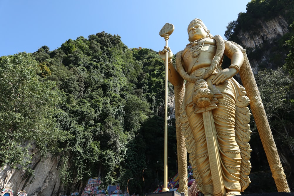 a statue of a man holding a lamp in front of a mountain