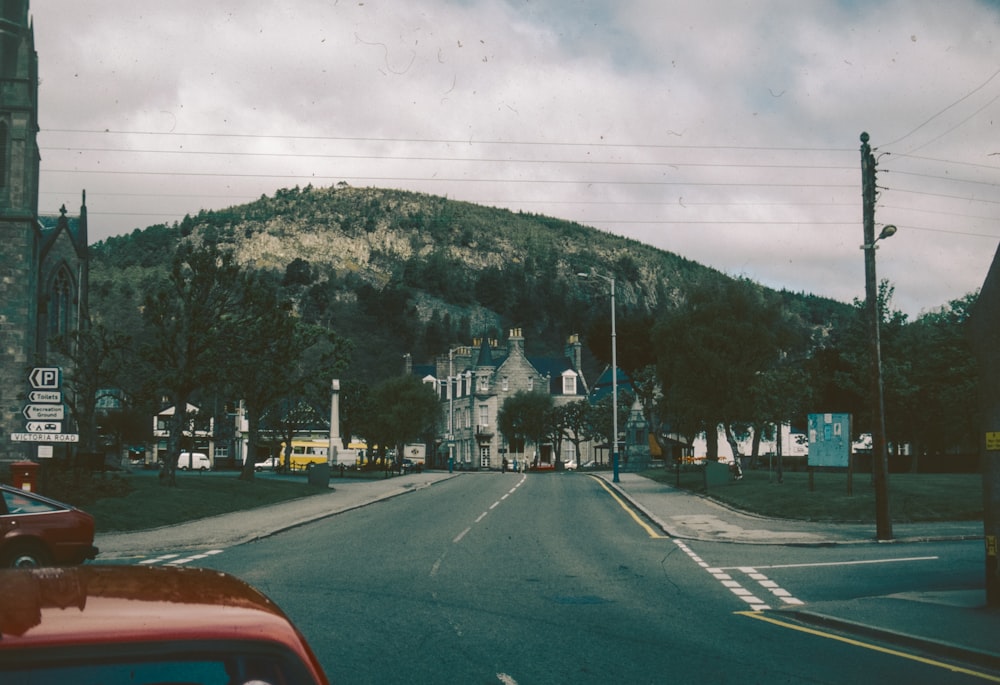 a car driving down a street next to a tall mountain