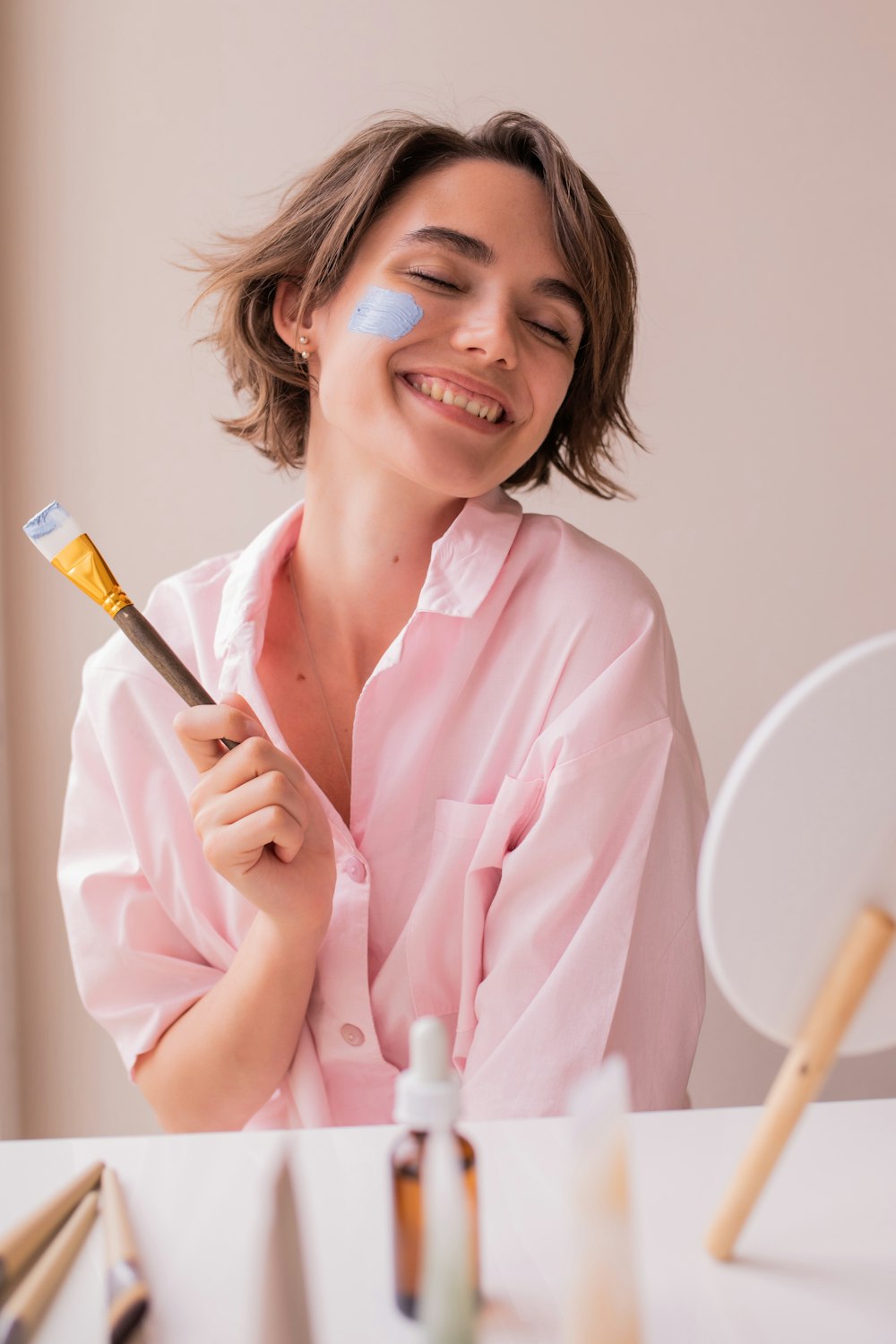 a woman smiling while holding a paintbrush