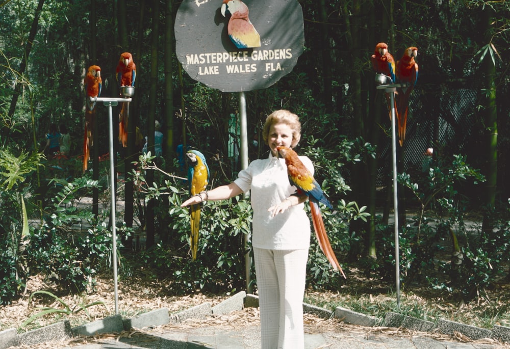 a woman standing in front of a sign with parrots on it