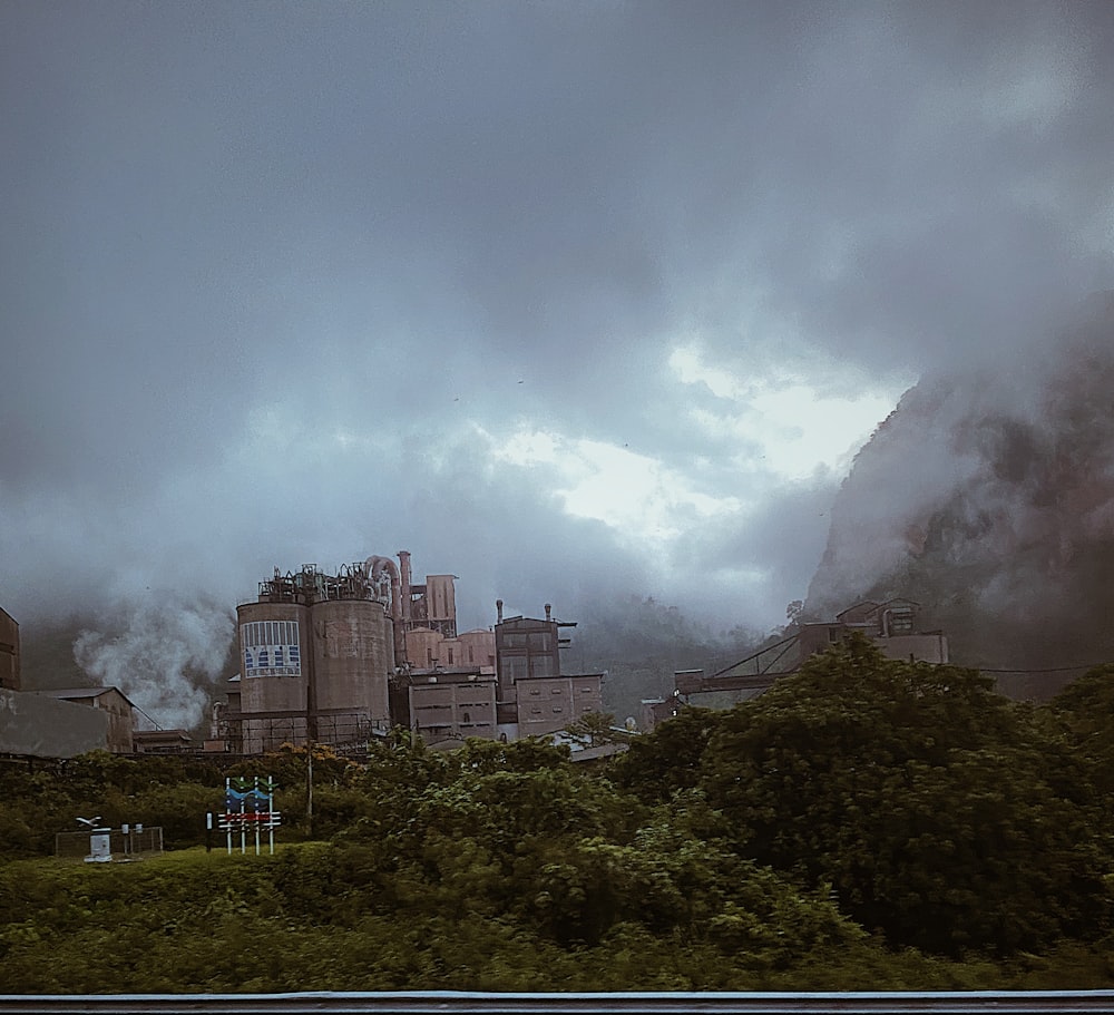 a train traveling past a factory on a cloudy day