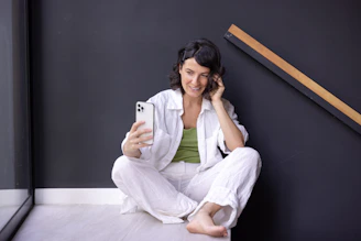 a woman sitting on the floor holding a cell phone