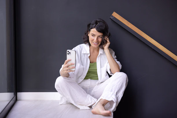 a woman sitting on the floor holding a cell phone