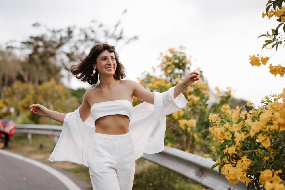 a woman in a white outfit is walking down a road