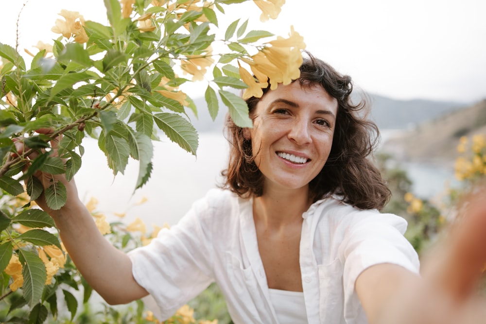 a woman holding onto a tree with yellow flowers on it