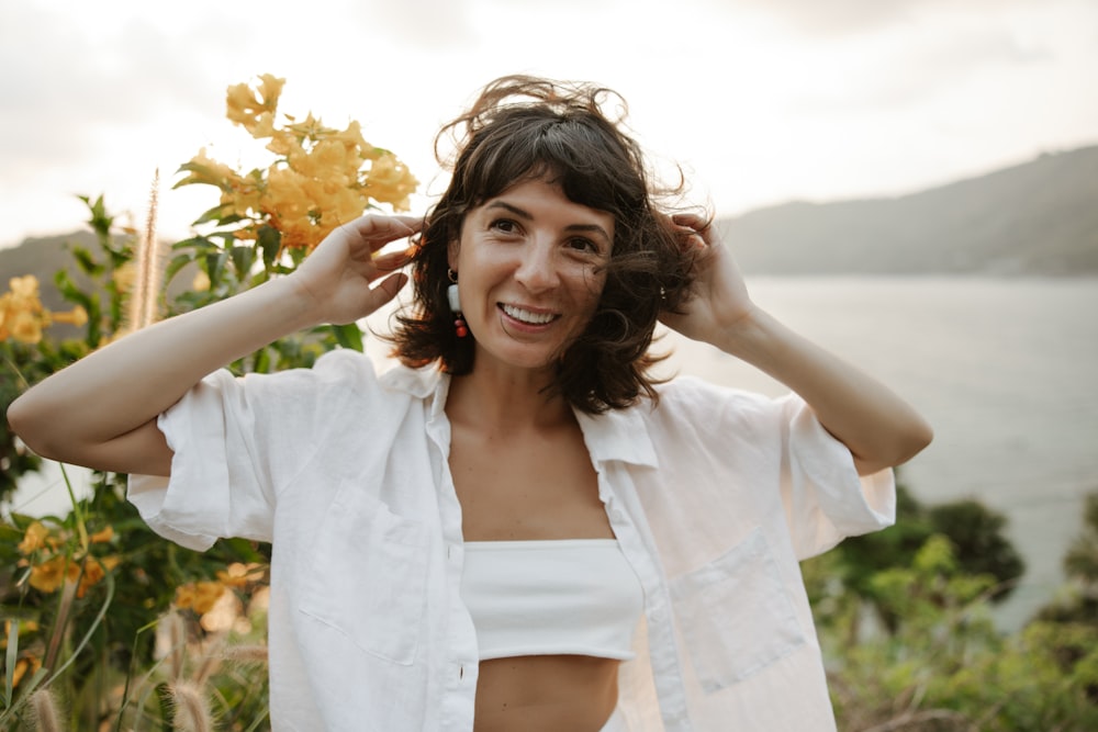 a woman in a white shirt is holding her hair