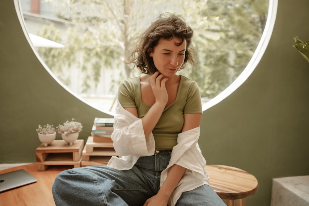 a woman sitting on a table in front of a round window