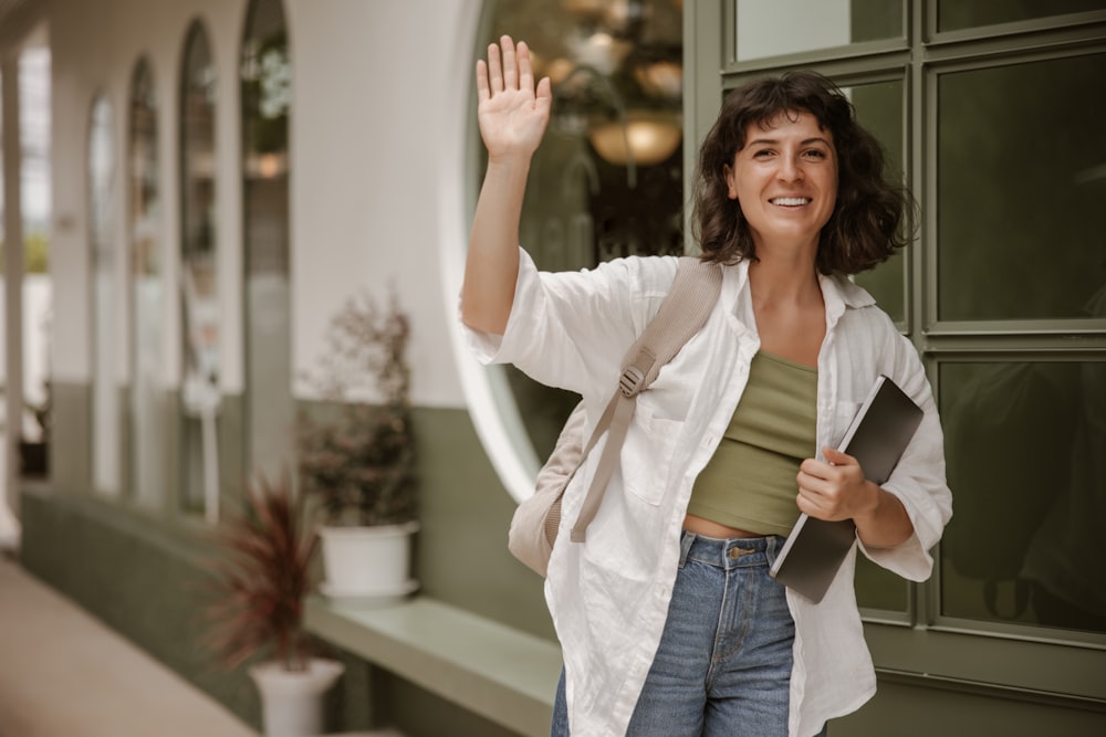 a woman is waving and holding her hand up