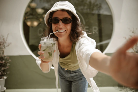 une femme en sweat-shirt blanc en train de boire un verre