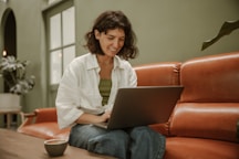 a woman sitting on a couch using a laptop computer