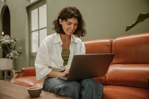 a woman sitting on a couch using a laptop computer