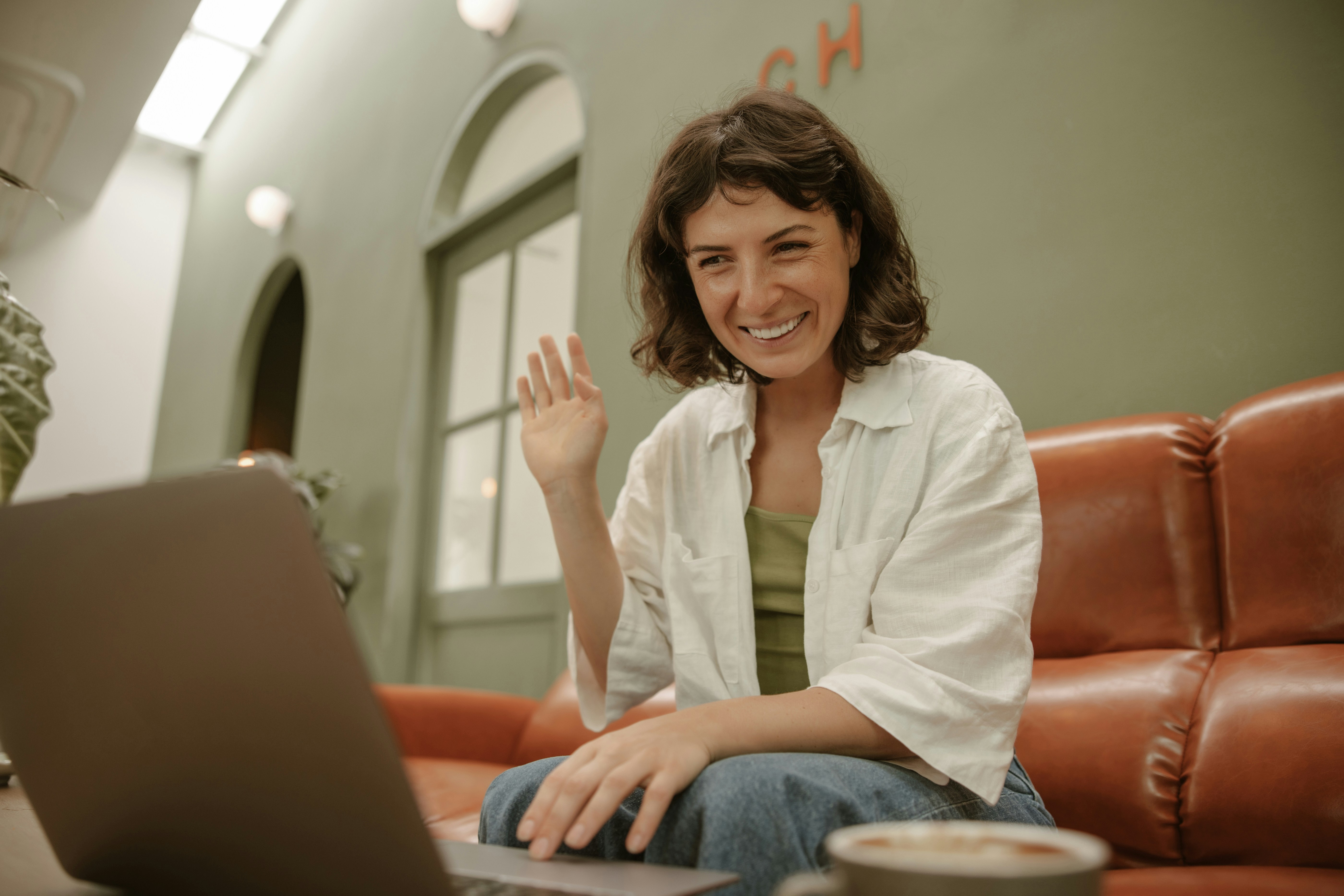 A woman sitting on a couch using a laptop for a video session
