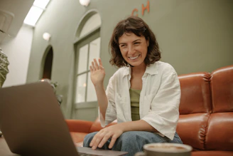a woman sitting on a couch using a laptop computer