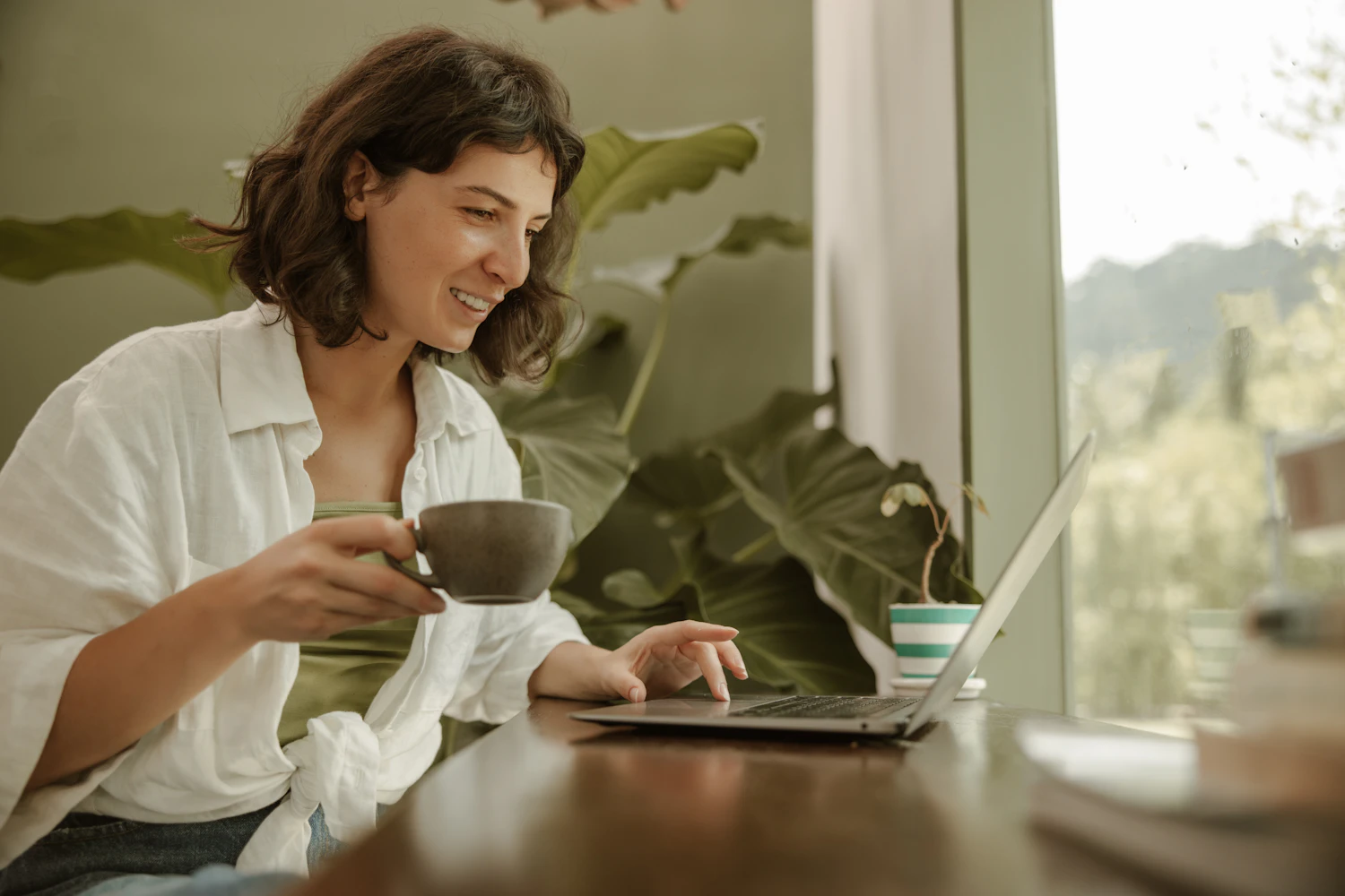 Frau arbeitet im Homeoffice mit Laptop und Kaffeetasse